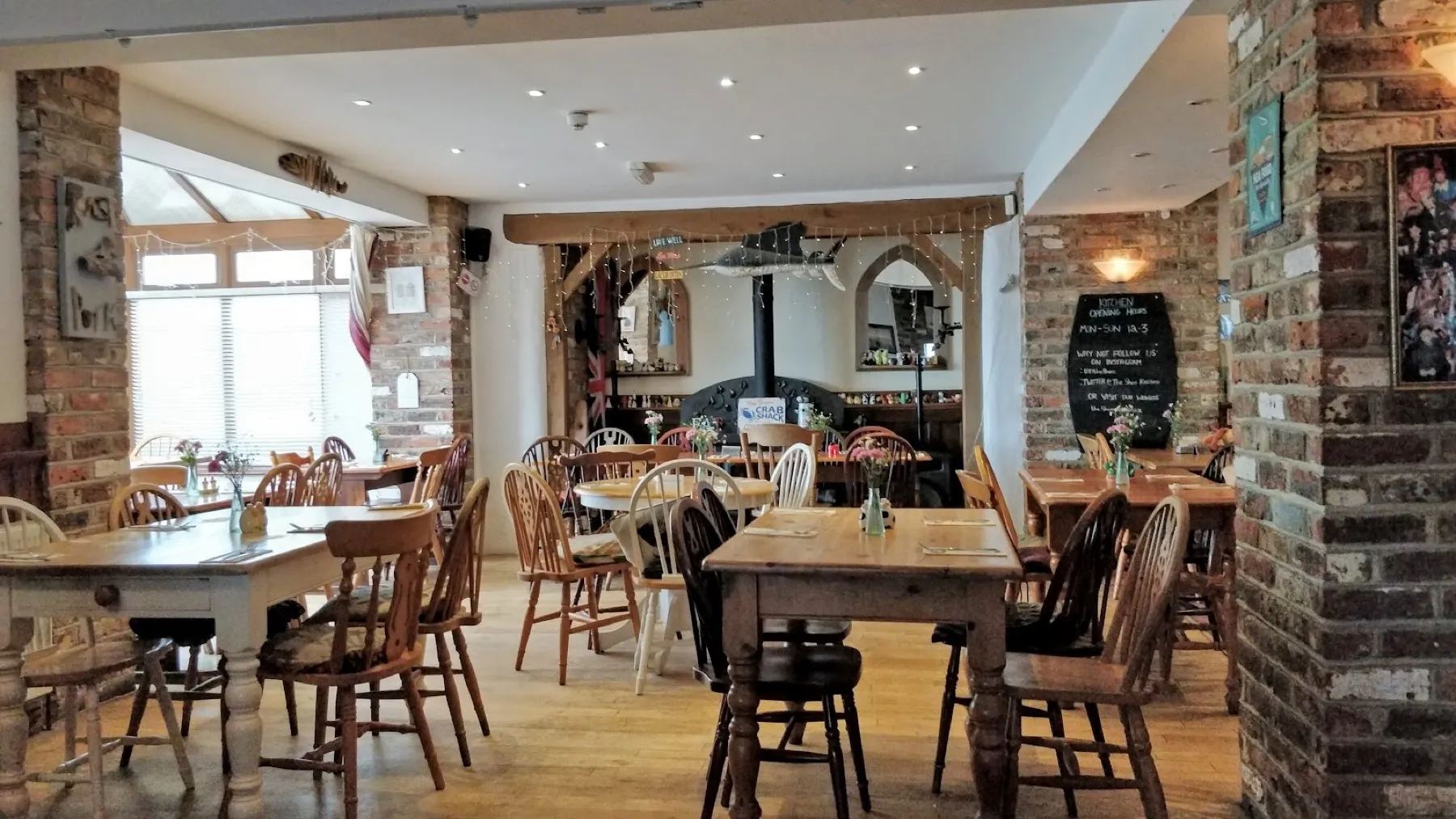Inside The Shore Inn: farmhouse tables, brick pillars and the marlin above the woodburner